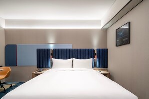Una camera d'hotel moderna con un letto grande, una scrivania con sedia, un telefono e una TV a parete.