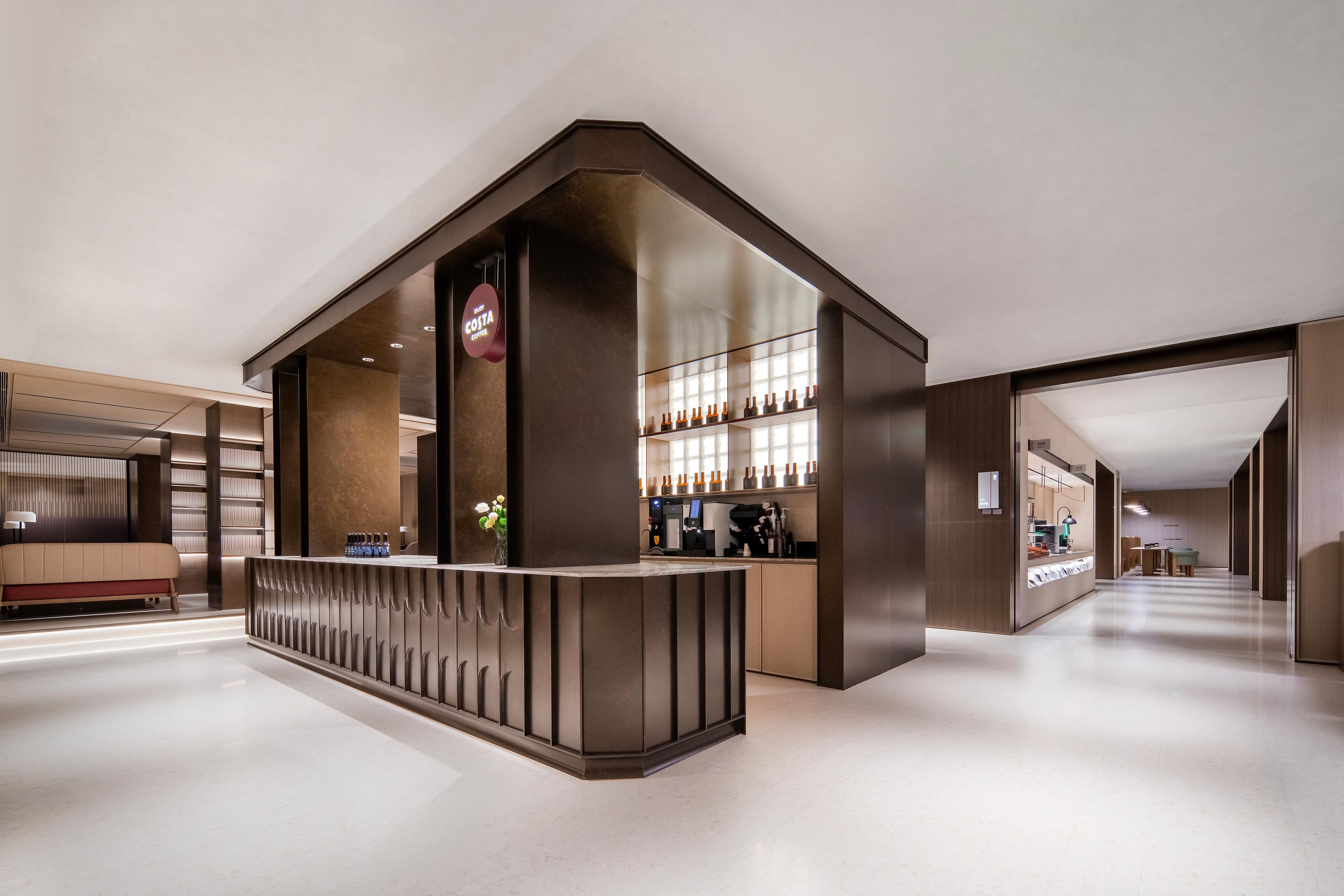 Un moderno vestíbulo de hotel con mostrador de recepción, zona de estar y bar.