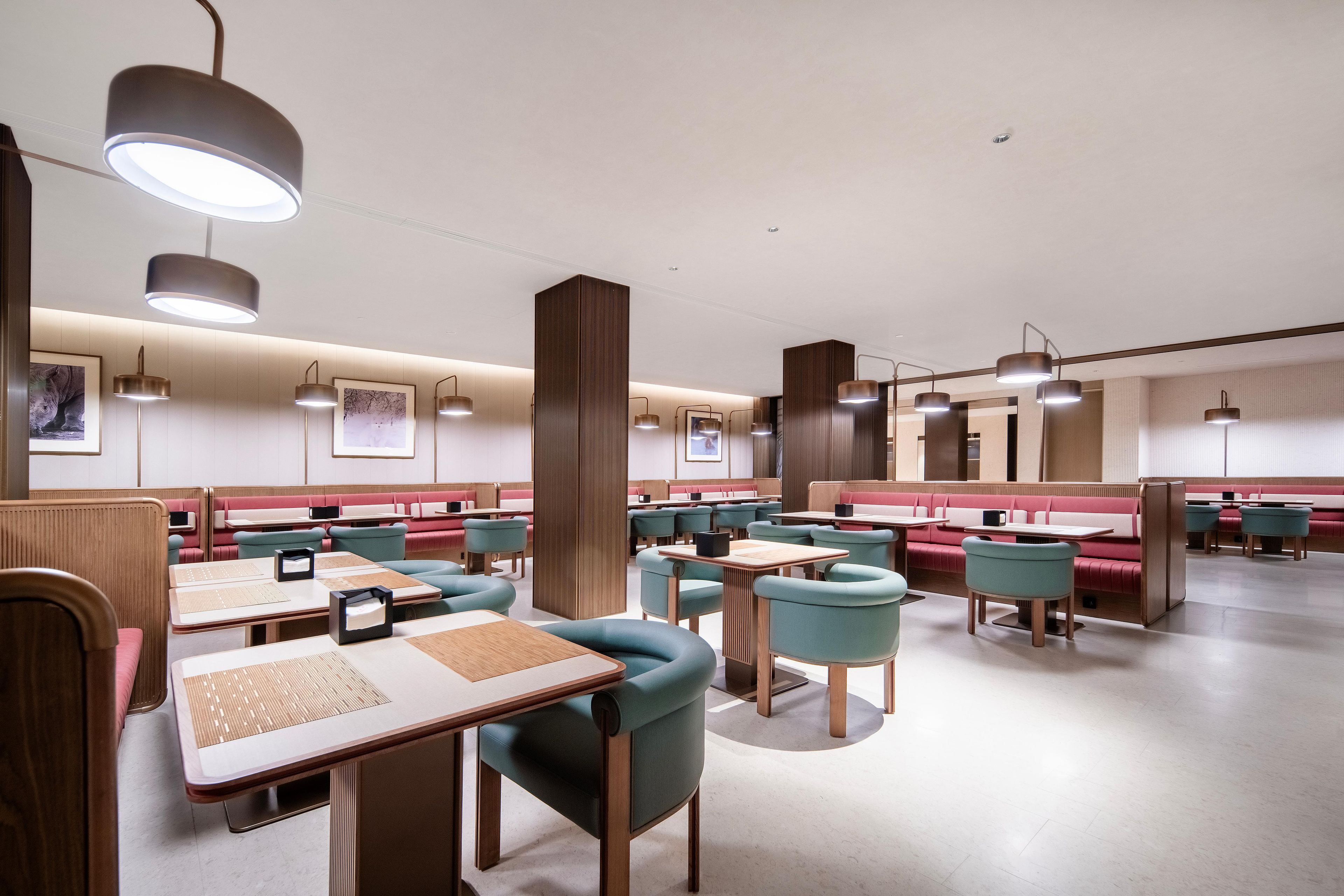 A modern restaurant with booths and tables, featuring pendant lighting and artwork on the walls.
