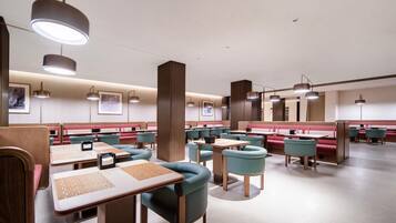 A modern restaurant with booths and tables, featuring pendant lighting and artwork on the walls.