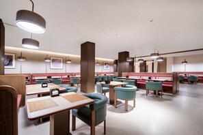 A modern restaurant with booths and tables, featuring pendant lighting and artwork on the walls.
