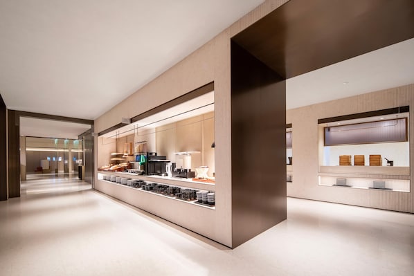 A modern hotel lobby with a long reception desk, glass partitions, and a clean, minimalist design.
