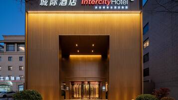 Het exterieur van het Intercity Hotel met een moderne gevel, een ruime entree en een bord met zowel Engelse als Chinese tekst.