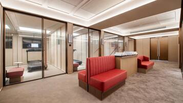 Een moderne hotel lobby met een rode bank, een klein tafeltje en een glazen scheidingswand.