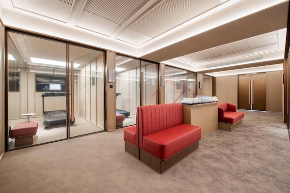 Eine moderne Hotellobby mit einem roten Sofa, einem kleinen Tisch und einer Trennwand aus Glas.