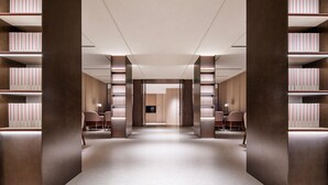 A modern library with bookshelves, a central elevator, and seating areas.