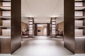 A modern library with bookshelves, a central elevator, and seating areas.
