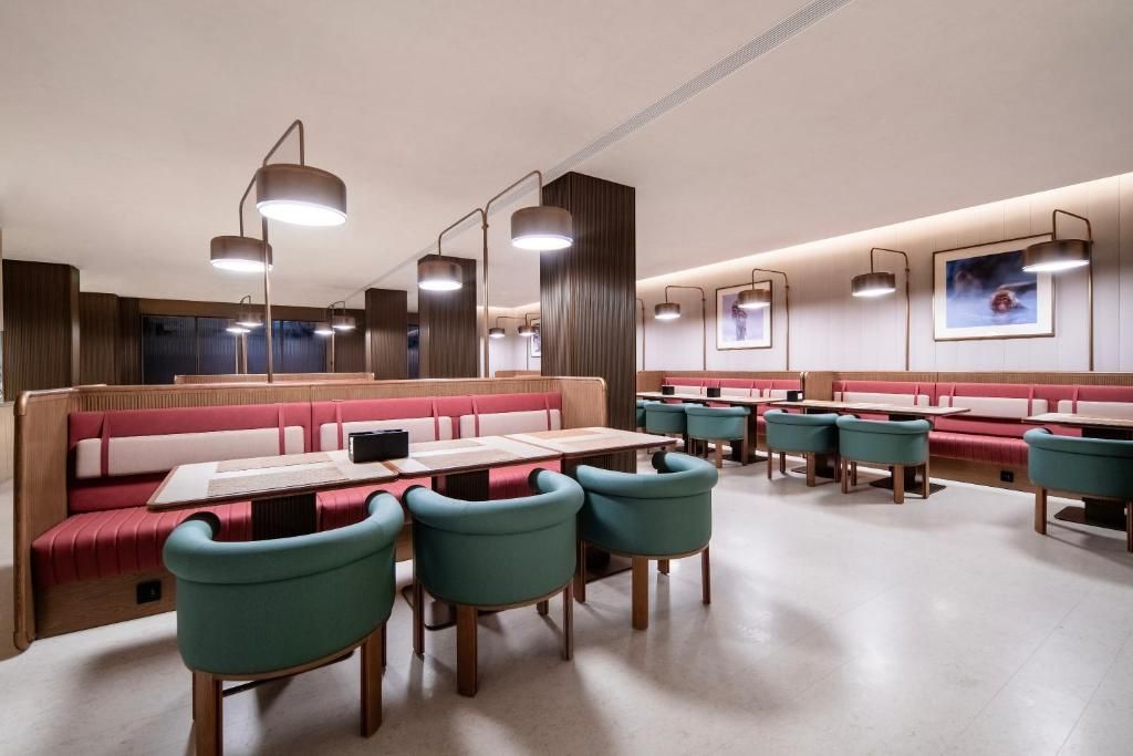A modern restaurant interior with booths and tables, pendant lighting, and framed artwork on the walls.