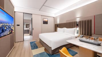 Una habitación de hotel moderna con una cama grande, un escritorio con teléfono y un televisor que muestra un paisaje urbano.