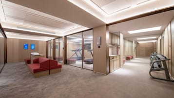 Un moderno vestíbulo de hotel con un sofá rojo, una recepción y una escalera que sube a un piso superior.