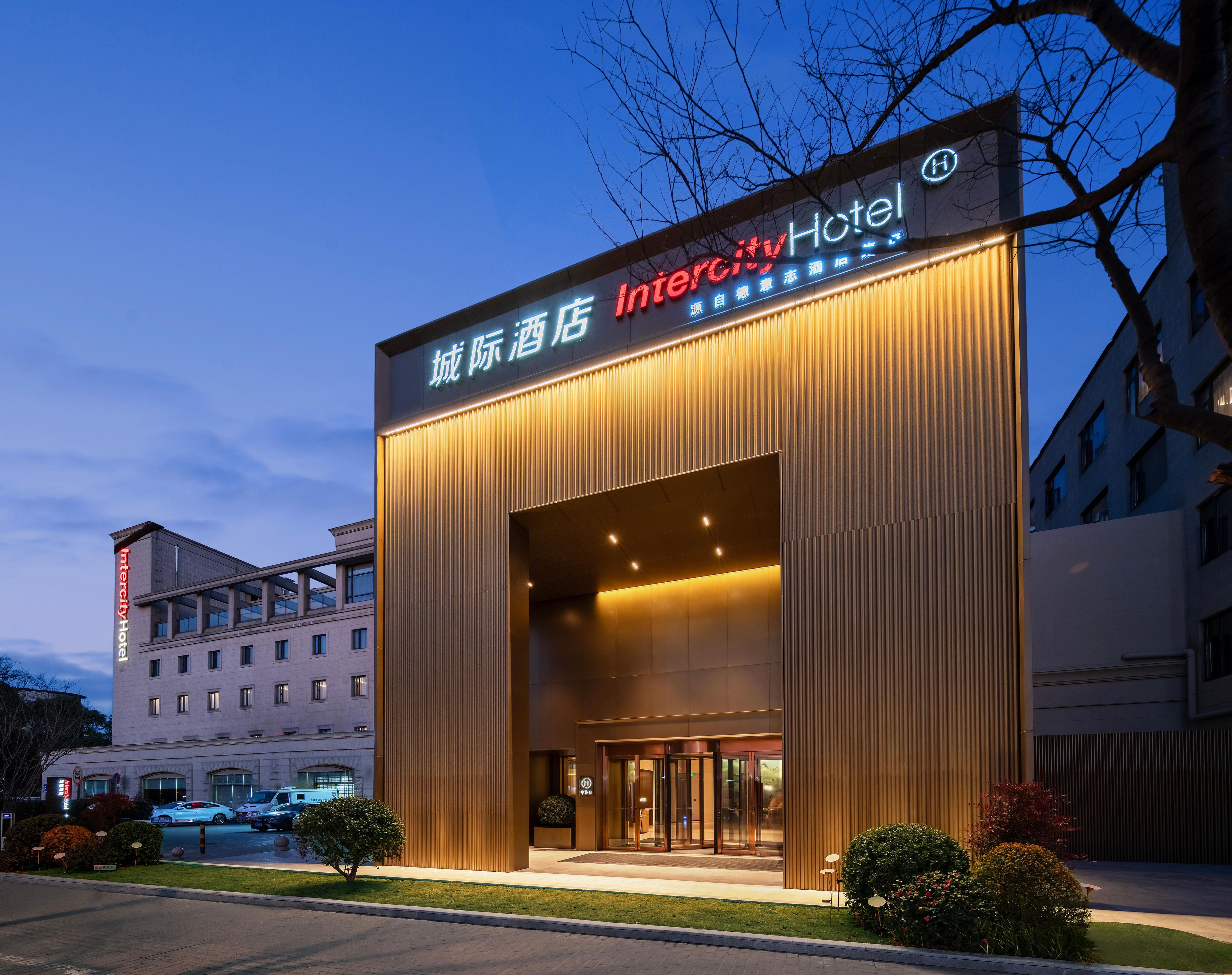 A modern hotel entrance with a large overhang and illuminated signage.