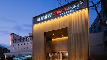 A modern hotel entrance with a large overhang and illuminated signage.