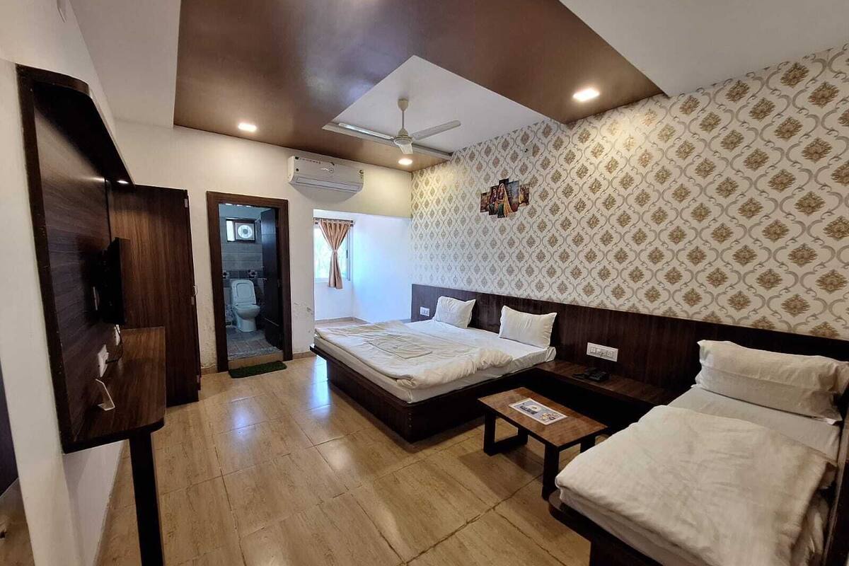 Une chambre d’hôtel avec un grand lit, une table de chevet, une armoire et une salle de bain visible à travers une porte ouverte.