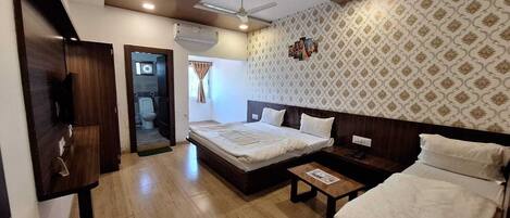 A hotel room with a large bed, a bedside table, a wardrobe, and a bathroom visible through an open door.