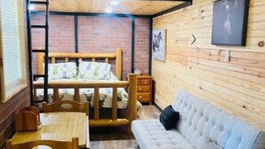A cozy cabin-style room with a bunk bed, a sofa, a dining table, and chairs. - Lovely Little Cabin in the Woods (Ocklawaha)