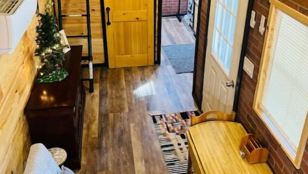 A cozy attic room with a wooden ceiling, a wooden table, a sofa, and a small Christmas tree. - Lovely Little Cabin in the Woods (Ocklawaha)