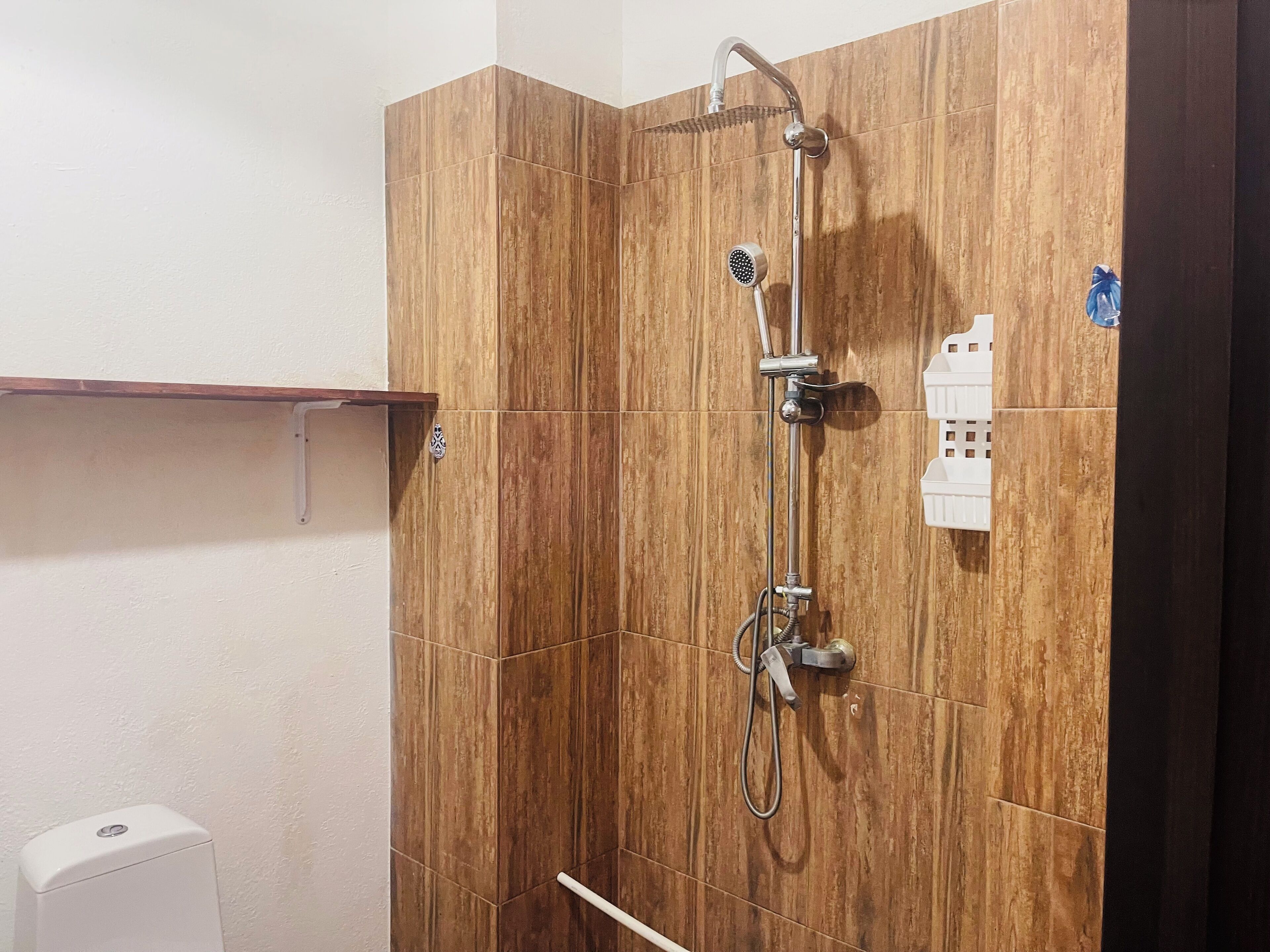 Ducha con paneles de madera, cabezal de ducha de mano y panel de control mural.