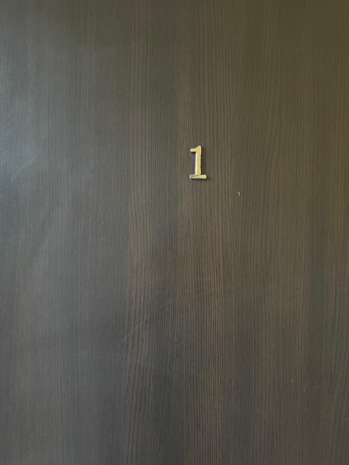 A dark wooden door with a brass number '1' handle.