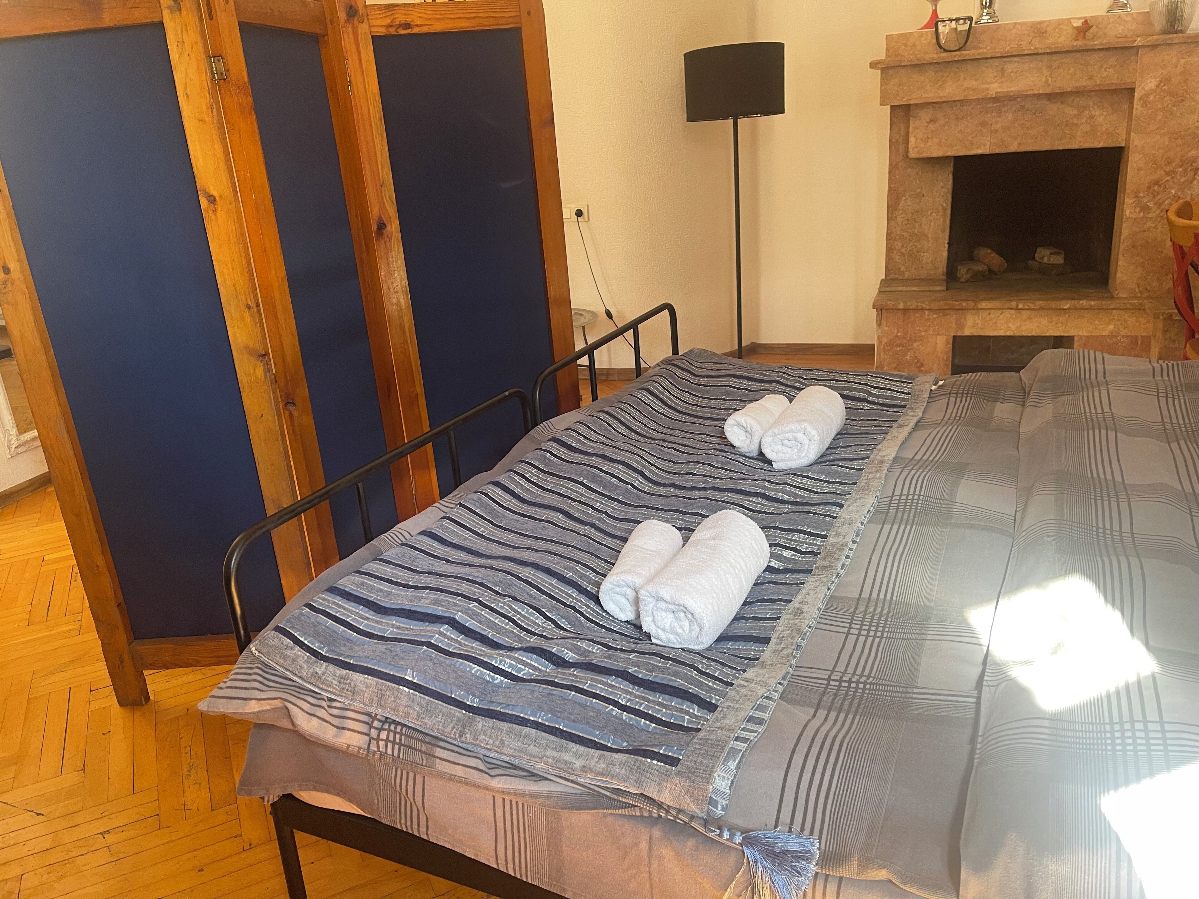 Une pièce comprenant un lit, une armoire en bois, une lampe sur pied et une cheminée.