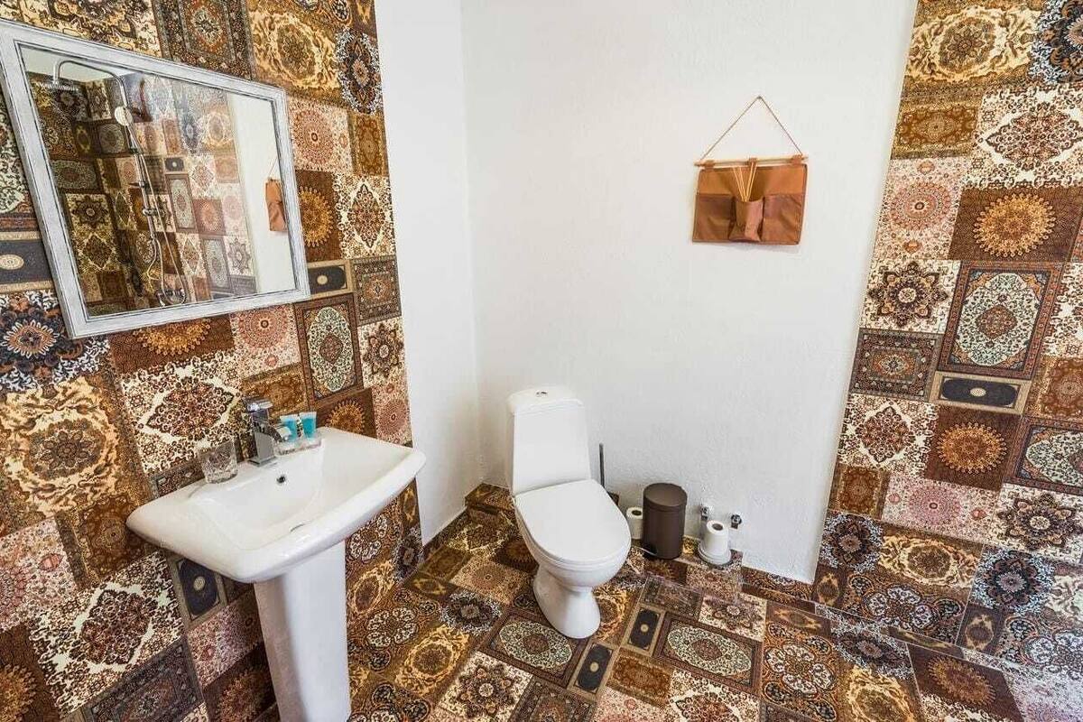 A bathroom with a patterned tile floor, a white sink, and a toilet.