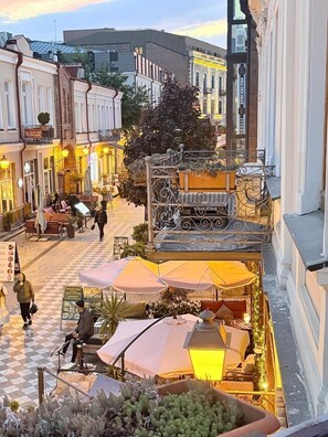 Vista a nivel de calle de un café con mesas al aire libre, rodeado de edificios históricos.