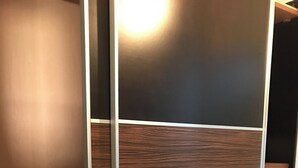 Een moderne kast met een houten paneelmotief en metalen handgrepen.