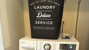 Een voorlader wasmachine van LG met een zwarte handdoek erboven, een digitaal display en een bedieningspaneel.
