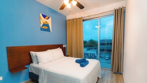 A hotel room with a bed, a ceiling fan, a window with curtains, and a view of the outside. - Charming 2-bedroom condo in Tulum with WiFi, AC (Tulum)