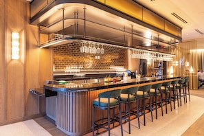 Enjoy a stylish bar experience with a sleek countertop, brick accent wall, and comfortable seating.