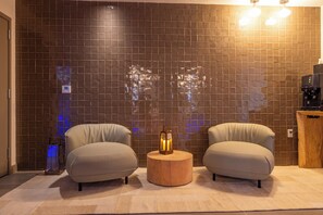 Relax in a stylish room with a unique wall feature, comfortable armchairs, and a sideboard.