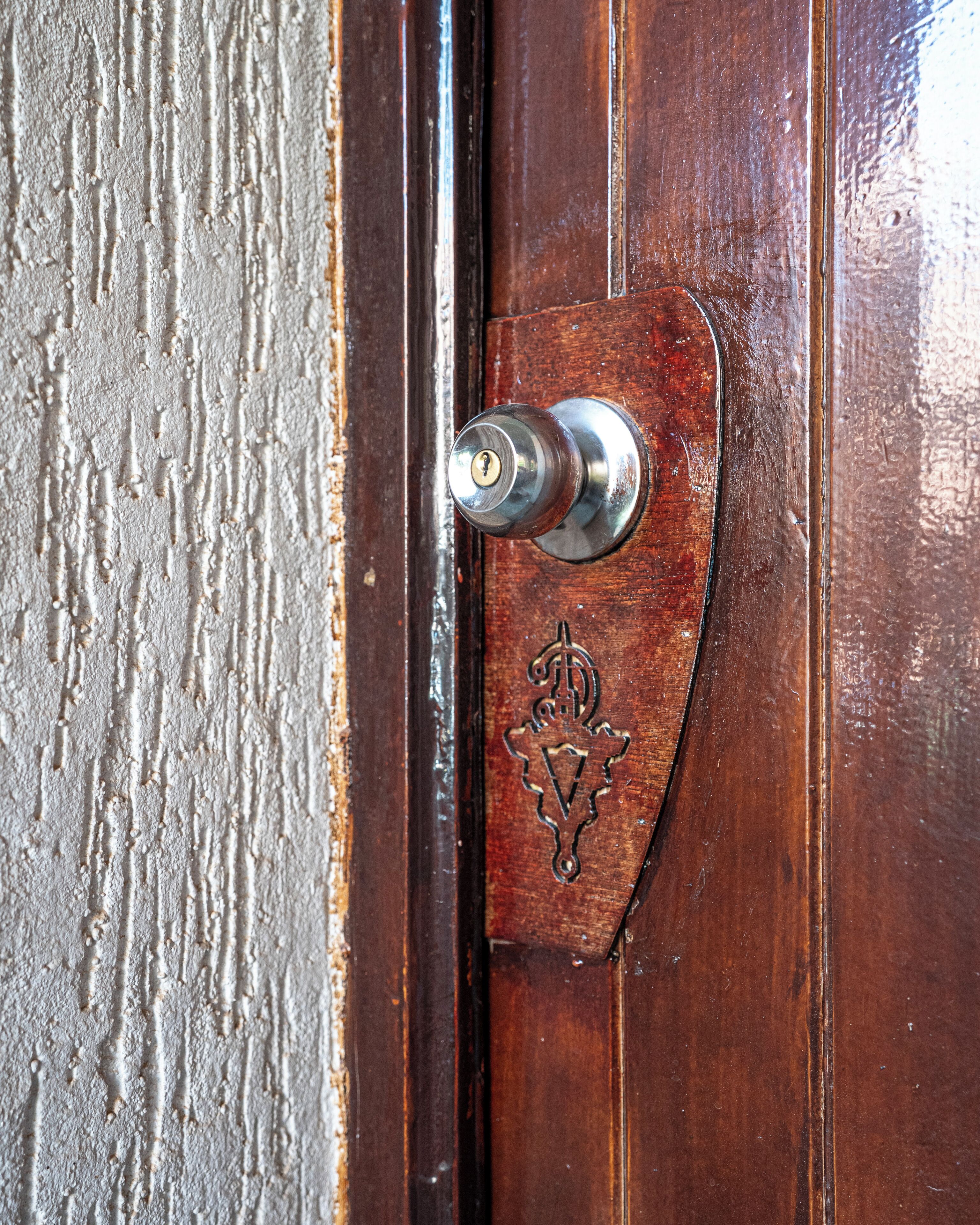 A wooden door with a metal door knocker and a decorative brass plate.