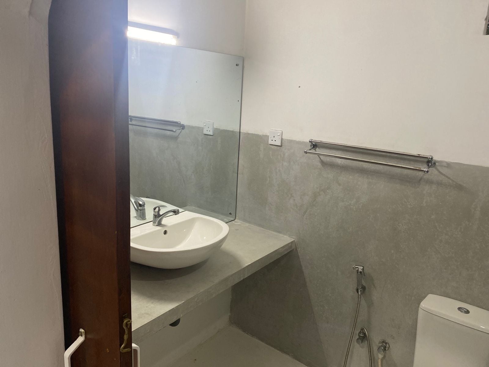 A bathroom with a white sink, a mirror, and a toilet.