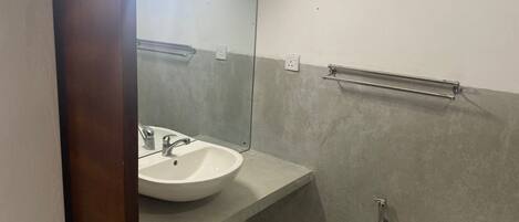A bathroom with a white sink, a mirror, and a toilet.