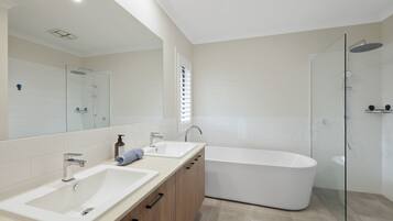 Ein modernes Badezimmer mit zwei Waschbecken, einer Badewanne und einer Duschkabine.