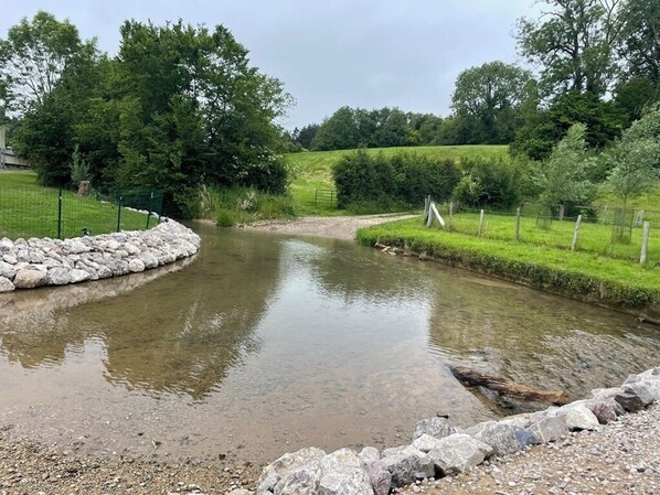 A small pond with a stone border and a grassy area with trees in the background. - House in the hollow of the Embryenne valley. (Boubers les hesmond (62990))