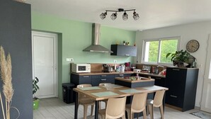 A modern kitchen with a dining area, featuring a microwave, stove, and cabinets. - House in the hollow of the Embryenne valley. (Boubers les hesmond (62990))