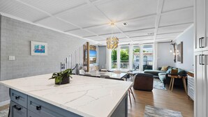 A modern kitchen with a marble countertop, a dining area with a view, and a living room with a sofa and a coffee table. - Back to the Beach (Miramar Beach)