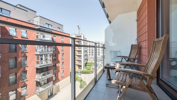 A balcony with a view of adjacent buildings, wooden chairs, and a small table. - Aura 39 by Grand Apartments (Gdansk)