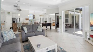 Ein großzügiger Wohnbereich mit grauem Sofa, weißem Couchtisch und Deckenventilator.