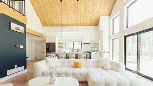 Een moderne woonkamer met een modulaire bank, een witte salontafel en een keuken op de achtergrond.