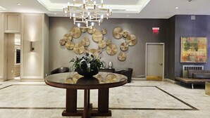Un hall d’entrée moderne avec une table ronde, un mur décoratif et un lustre.