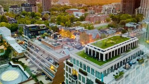 Un bâtiment moderne doté d’un jardin sur le toit, entouré d’autres immeubles et de verdure.
