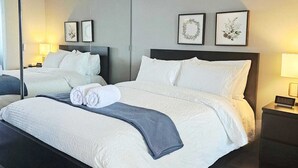 Une chambre d’hôtel moderne avec un grand lit, un parquet en bois foncé et un grand miroir sur un des murs.