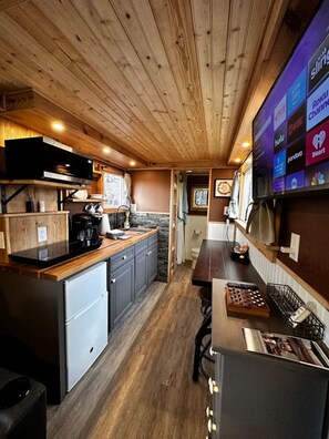 A compact kitchen with wooden cabinetry, a built-in microwave, and a coffee maker.