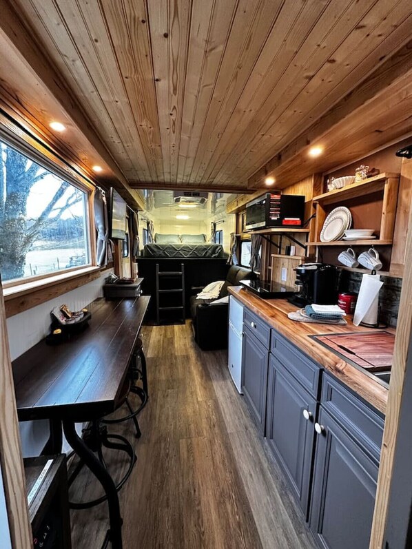 A compact RV interior with a kitchenette, a dining area, and a sleeping space.