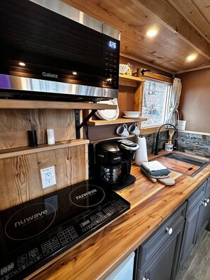 Une cuisine compacte équipée d’un four à micro-ondes Galanz, d’une plaque de cuisson à induction Nuwave et d’une machine à café Keurig.