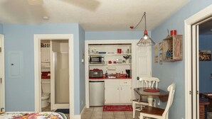 A compact kitchen with white cabinets, a microwave, and a sink. There's a dining area with a table and chairs. - StoneFly Studio at Dragonfly Flats  Creede, Co (Creede)
