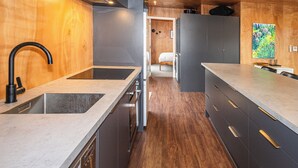 A modern kitchen with a wooden ceiling, a built-in dishwasher, and a dining area with a table and chairs. - Mountain Haus - Ohakune Holiday Home (Ohakune)