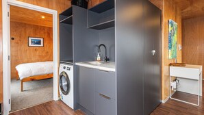 A compact bedroom with a washing machine, a small sink, and a bed. - Mountain Haus - Ohakune Holiday Home (Ohakune)