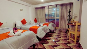 A hotel room with two beds, each with white bedding and orange accents, a wooden chair, a small table with a vase, and a large window with a view of the city. - Hotel La Florida  (Cusco)